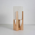 Short Clérachic table lamp in natural wood, its fabric shade close to the frame, shown on a grey backdrop.