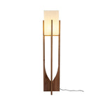 Tall Clérachic floor lamp in a dark walnut tone, lit, with a long black cord curling at its foot, on white.