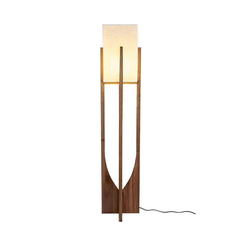 Tall Clérachic floor lamp in a dark walnut tone, lit, with a long black cord curling at its foot, on white.