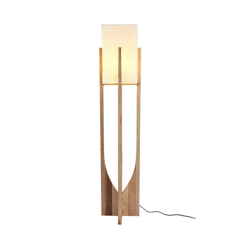 Tall Clérachic floor lamp in natural ash with a softly lit shade and a black cord on the floor, on a white backdrop.