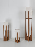 Three Clérachic lamps in different heights stand together against a pale wall, all with unlit white fabric shades.