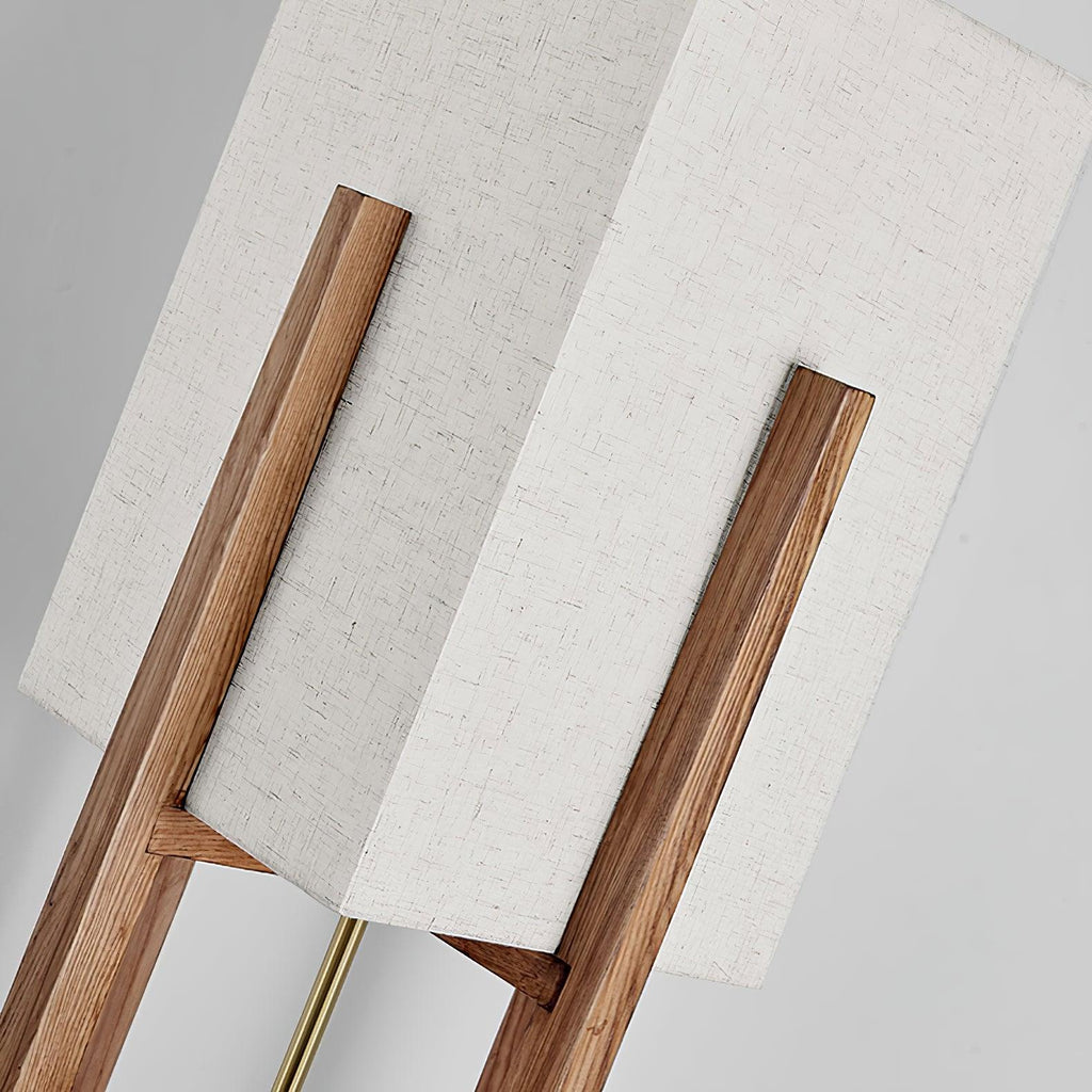 Close view of the white fabric shade and the angled wooden frame on this Clérachic lamp, with a brass rod below.