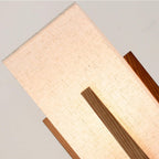 Close view of the lit fabric shade with a wooden upright in front, showing the weave of the linen on this Clérachic lamp.