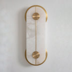The Clérachic Auriel shows the veining in its alabaster panel, held top and bottom by brushed brass crescents against an off-white wall.