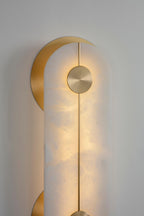 The Clérachic wall light in close crop, the brushed brass knob and central rod catching light where they cross the lit alabaster.