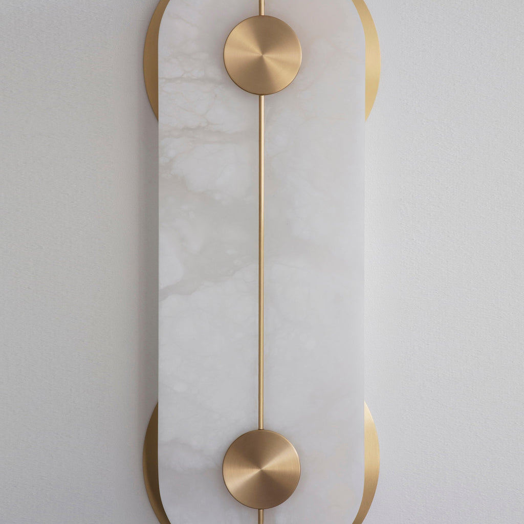 Clérachic Auriel in tight detail, the brushed brass disc and slender rod set flush against the cool white alabaster face.