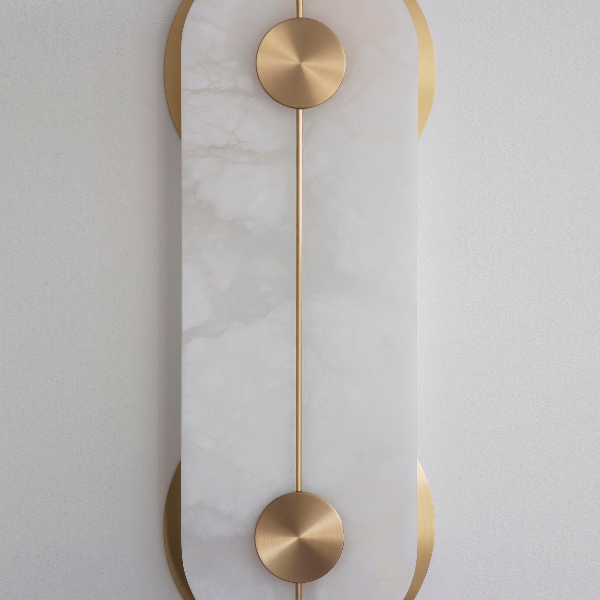 Clérachic Auriel in tight detail, the brushed brass disc and slender rod set flush against the cool white alabaster face.