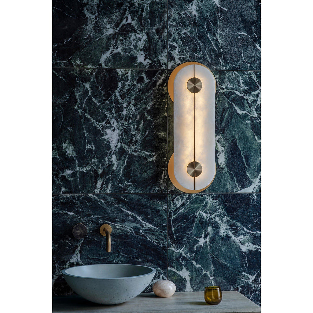 Clérachic Auriel mounted on veined green marble above a washbasin, its warm glow lifting the white marbling in the stone.
