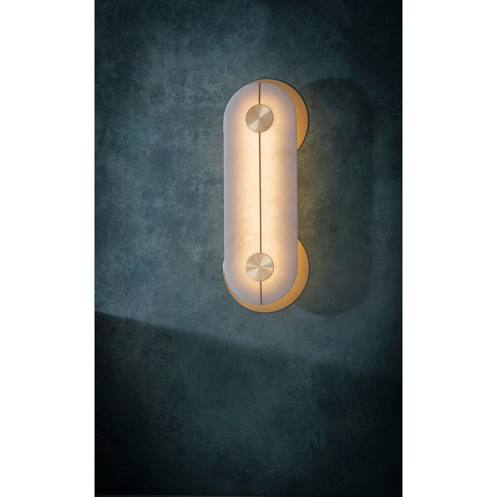 Clérachic Auriel alight on a bare concrete wall, the alabaster throwing a wide, even wash across the rough surface.