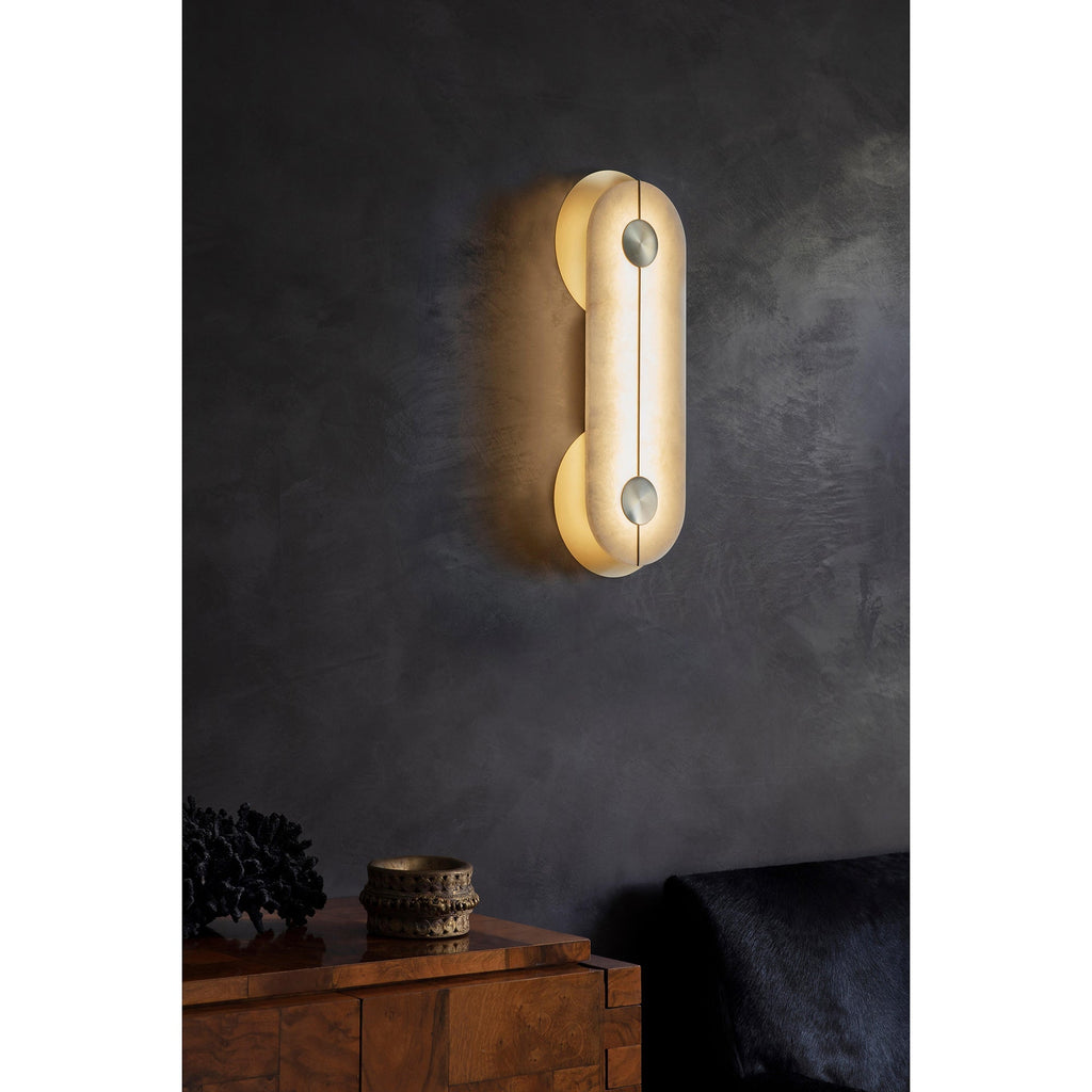 Clérachic Auriel lighting a dark plaster wall above a walnut sideboard, its warm capsule of alabaster anchoring the corner.