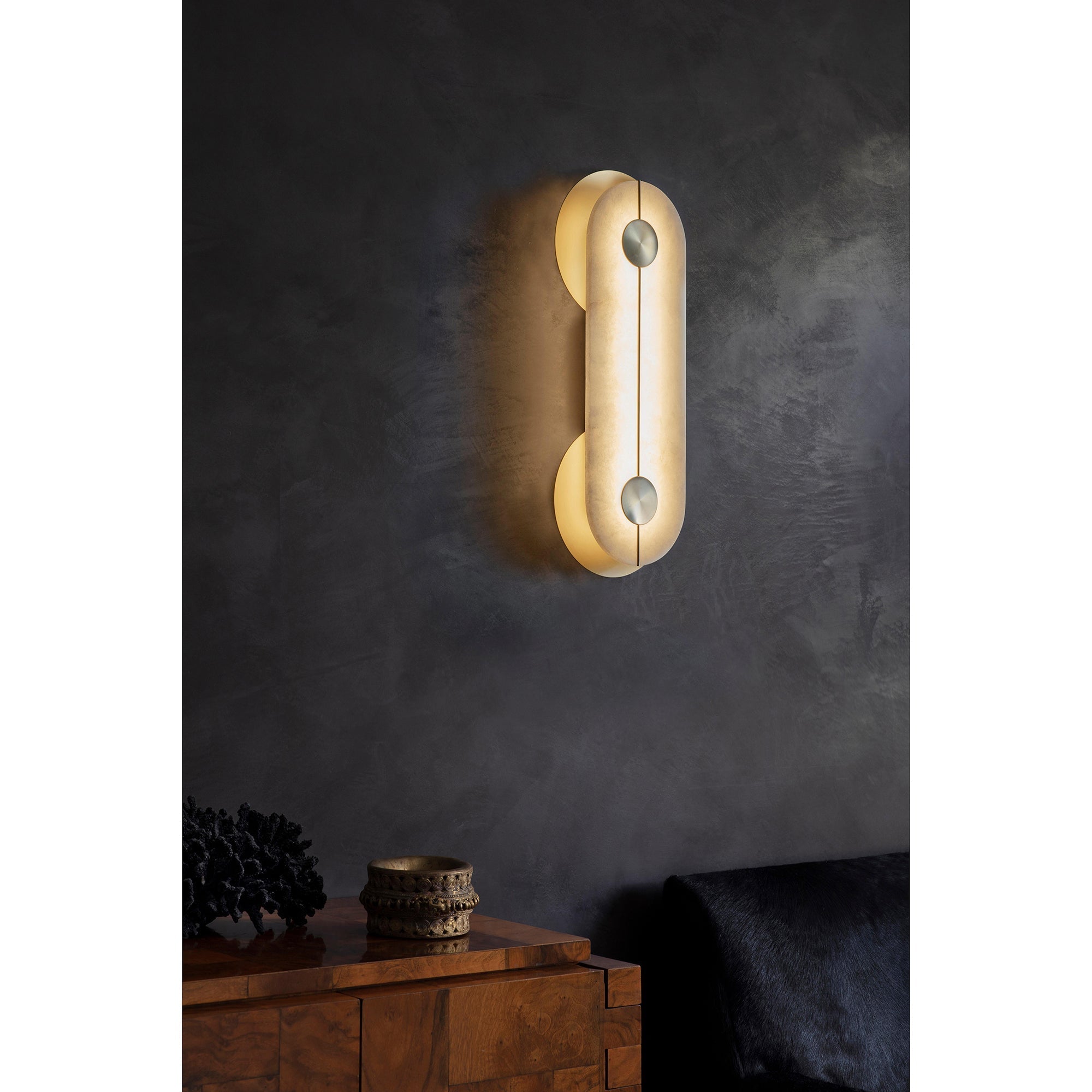 Clérachic Auriel lighting a dark plaster wall above a walnut sideboard, its warm capsule of alabaster anchoring the corner.