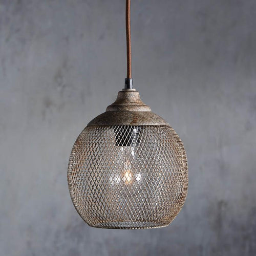A Clérachic rust mesh pendant glows softly against a weathered gray backdrop.