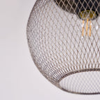A close-up reveals the Clérachic mesh cage's fine diamond weave around a glowing bulb.