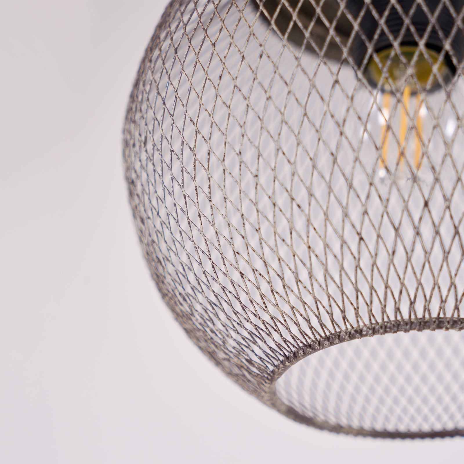 A close-up reveals the Clérachic mesh cage's fine diamond weave around a glowing bulb.