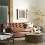 A single Clérachic mesh pendant hangs beside framed art in a warm, leather-sofa living room.