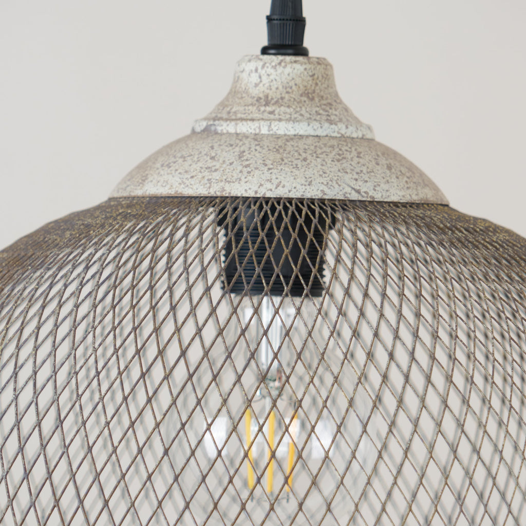 This close-up shows the Clérachic pendant's ceiling cap and glowing filament bulb inside the cage.