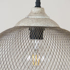 This close-up shows the Clérachic pendant's ceiling cap and glowing filament bulb inside the cage.