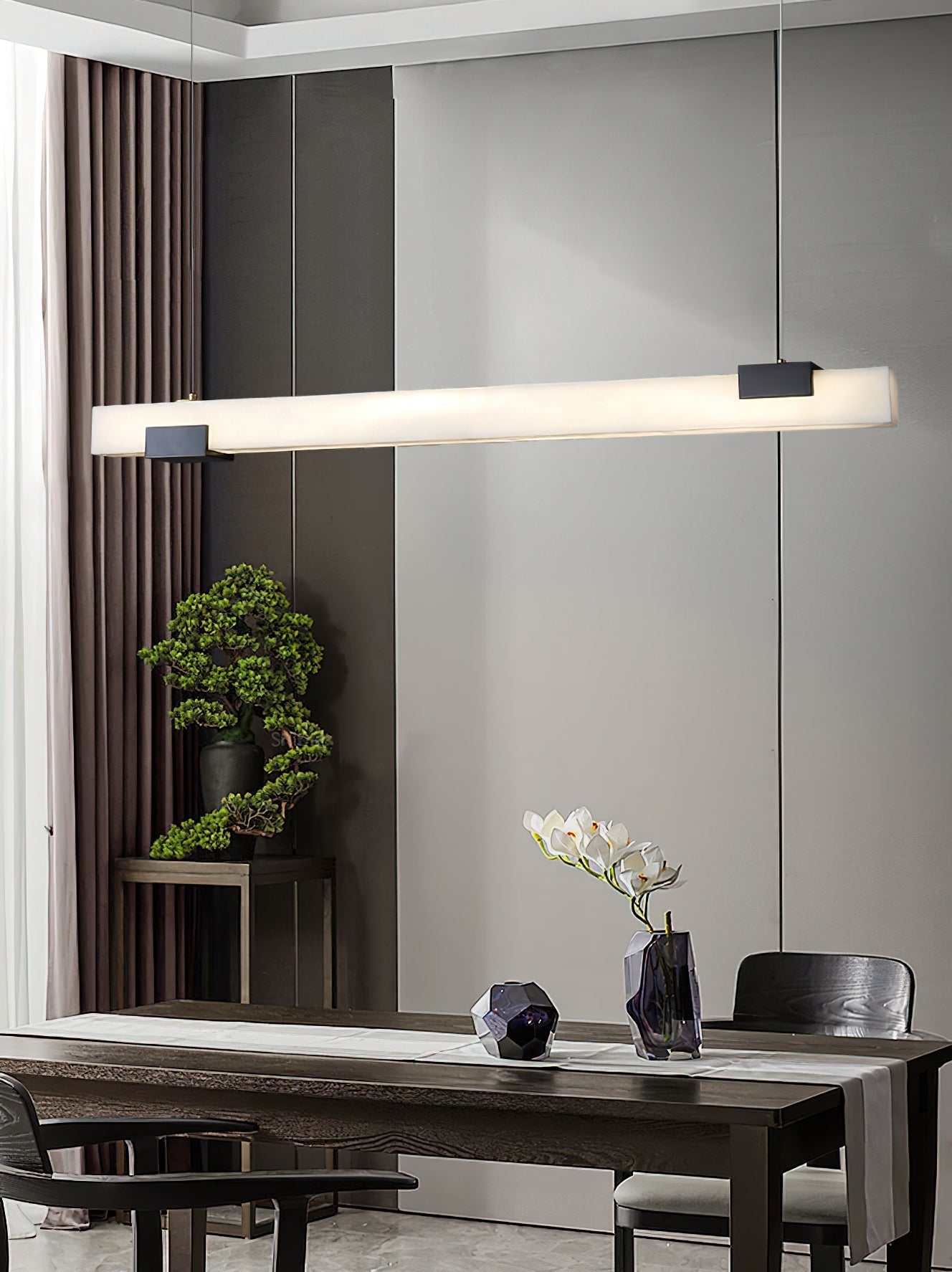 Clérachic Avert hung over a dark timber dining table, a bonsai and white orchid catching its soft wash of light.