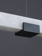 Close view of the Clérachic Avert's matte black brass saddle clamped over the alabaster bar's translucent edge.