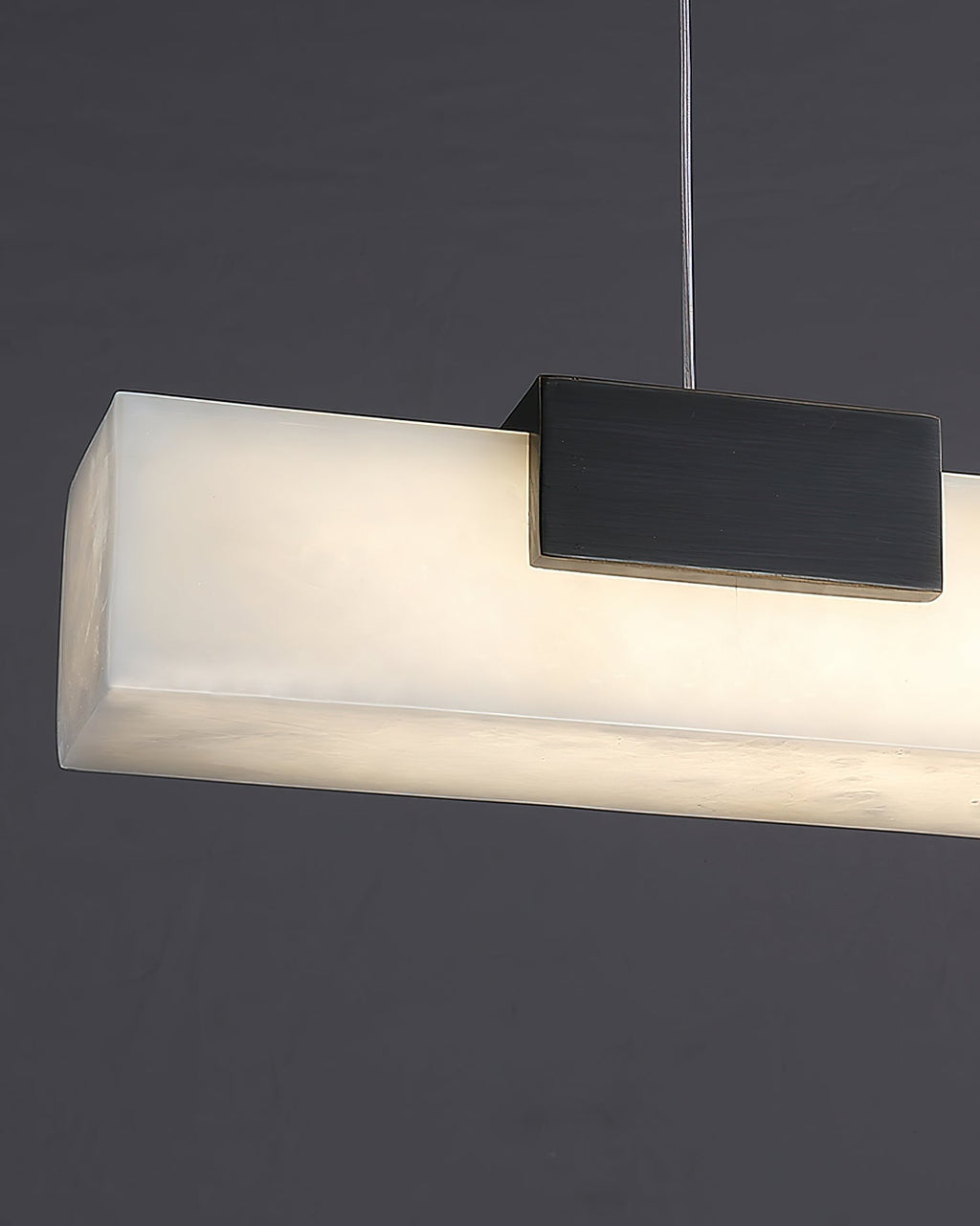 The Clérachic Avert seen end on, the lit alabaster bar glowing warm beside its blackened brass block mount.