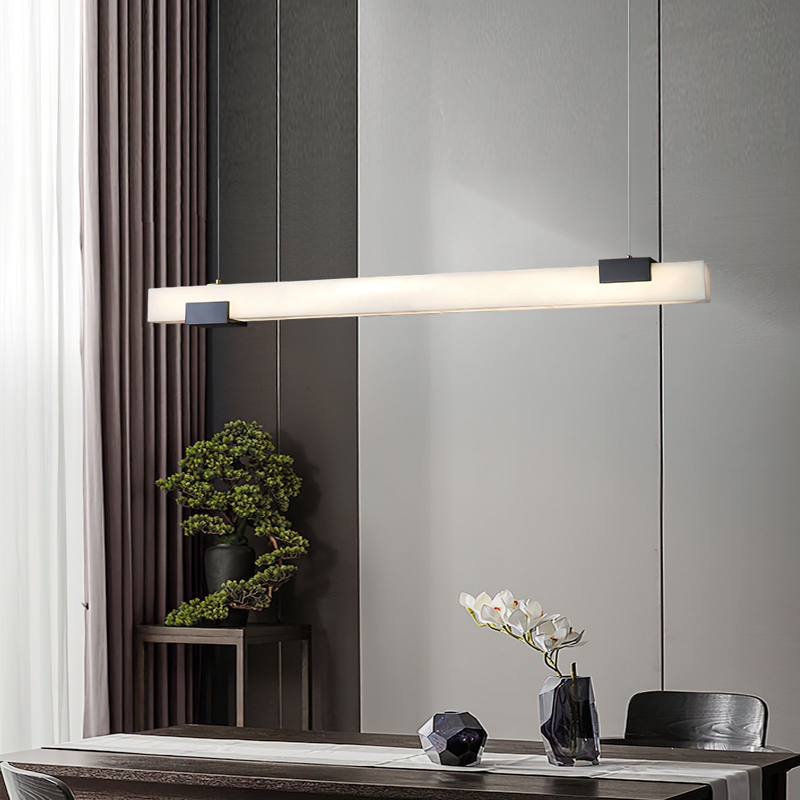 Clérachic Avert stretched above a dining table, the fluted wall and bonsai lit by its long, glare-free bar.