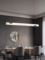 Clérachic Avert in a wide dining room, its warm bar of light held against a deep charcoal plaster wall.