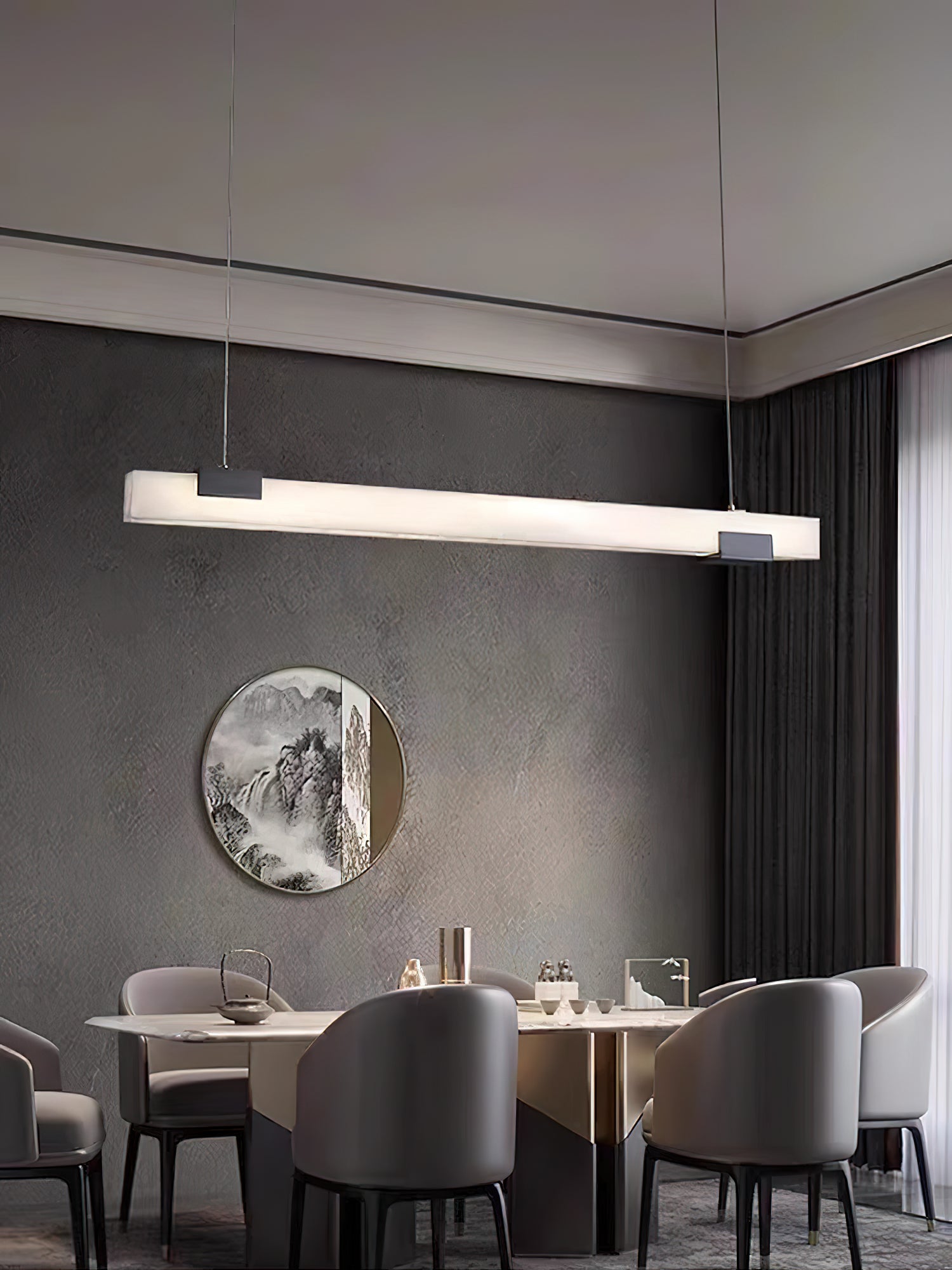 Clérachic Avert in a wide dining room, its warm bar of light held against a deep charcoal plaster wall.