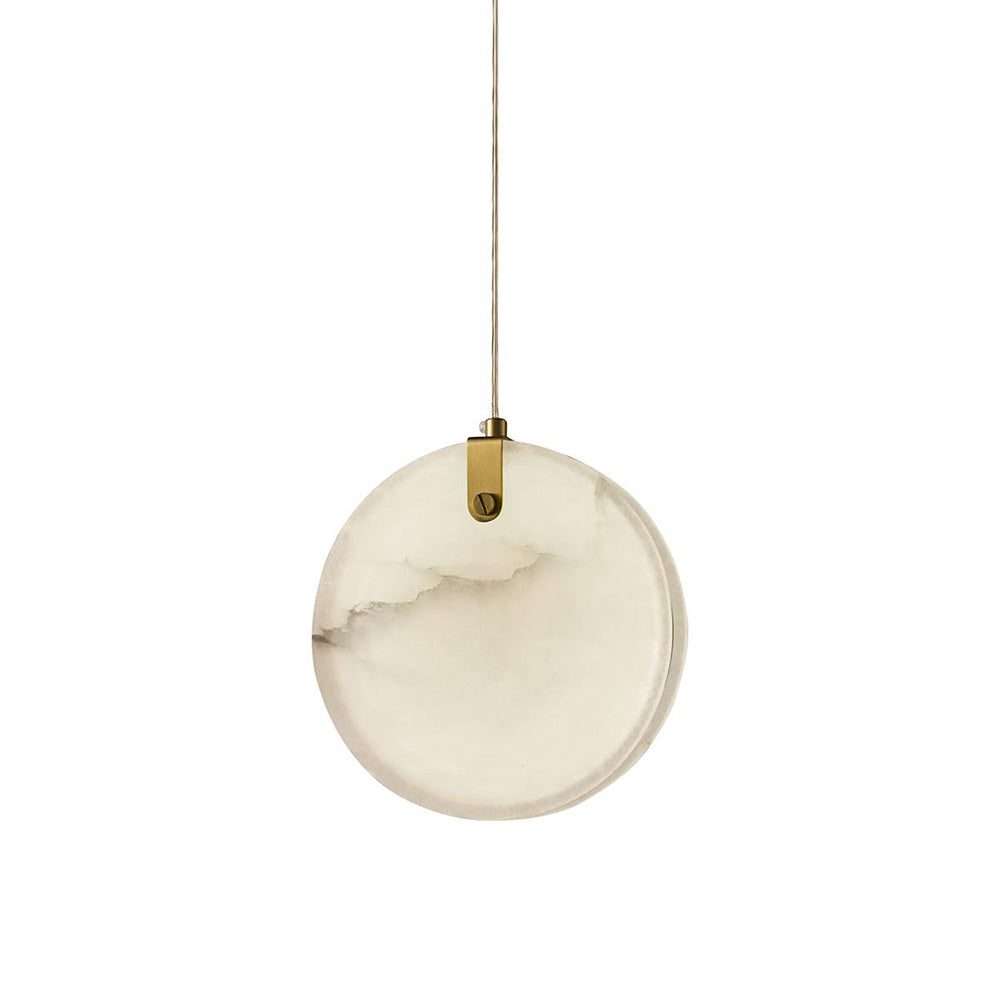 A single Clérachic alabaster disc pendant on white, its brass strap gripping the top edge of the stone on one slotted pin.