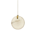 A single Clérachic alabaster disc pendant on white, its brass strap gripping the top edge of the stone on one slotted pin.
