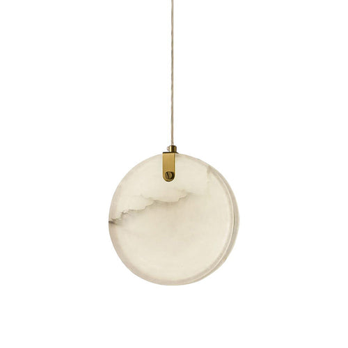 A single Clérachic alabaster disc pendant on white, its brass strap gripping the top edge of the stone on one slotted pin.