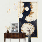 Four Clérachic alabaster pendants at staggered drops over a dark wood sideboard, brass rims catching the light.
