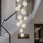The Clérachic multi-head alabaster pendant spiralling down a white stairwell, twelve discs lit warm from within.