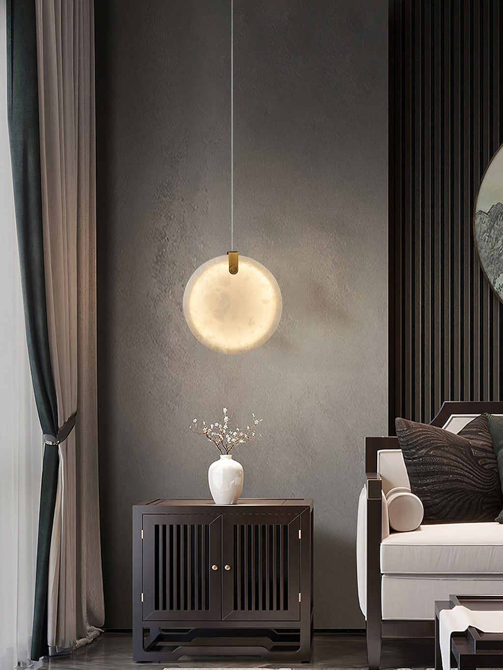 A Clérachic alabaster pendant lit above a dark wood cabinet, its glow spreading across a grey textured wall.