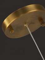 Close-up of the Clérachic pendant's round brass canopy from below, showing the cable thumbscrews that set the drop.