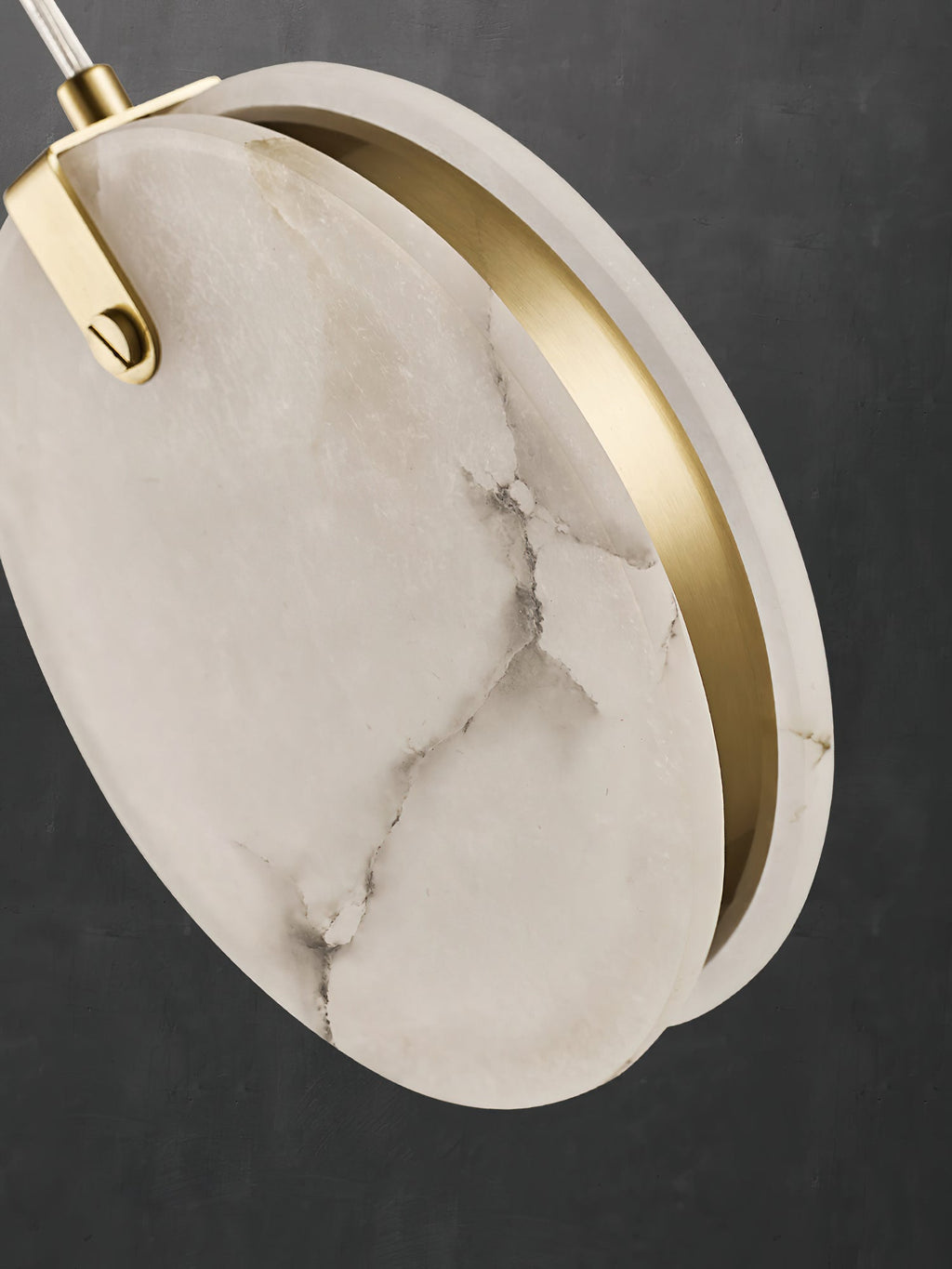 Angled close-up of a Clérachic alabaster disc, two slices of stone with a slim brass ring set between them.