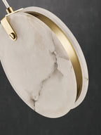 Angled close-up of a Clérachic alabaster disc, two slices of stone with a slim brass ring set between them.