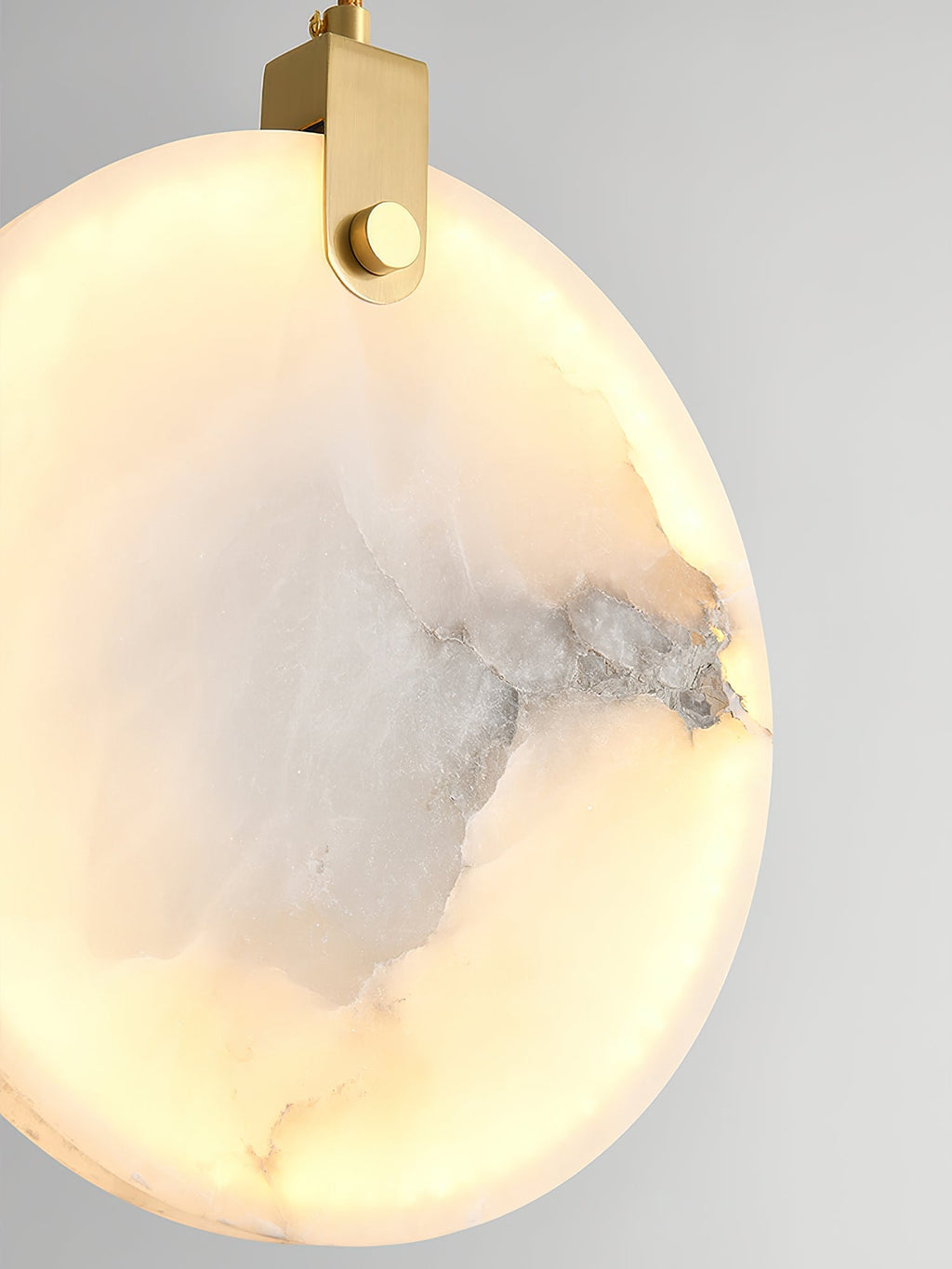 Close-up of a lit Clérachic alabaster disc, grey veining surfacing as dark seams inside the glowing stone.