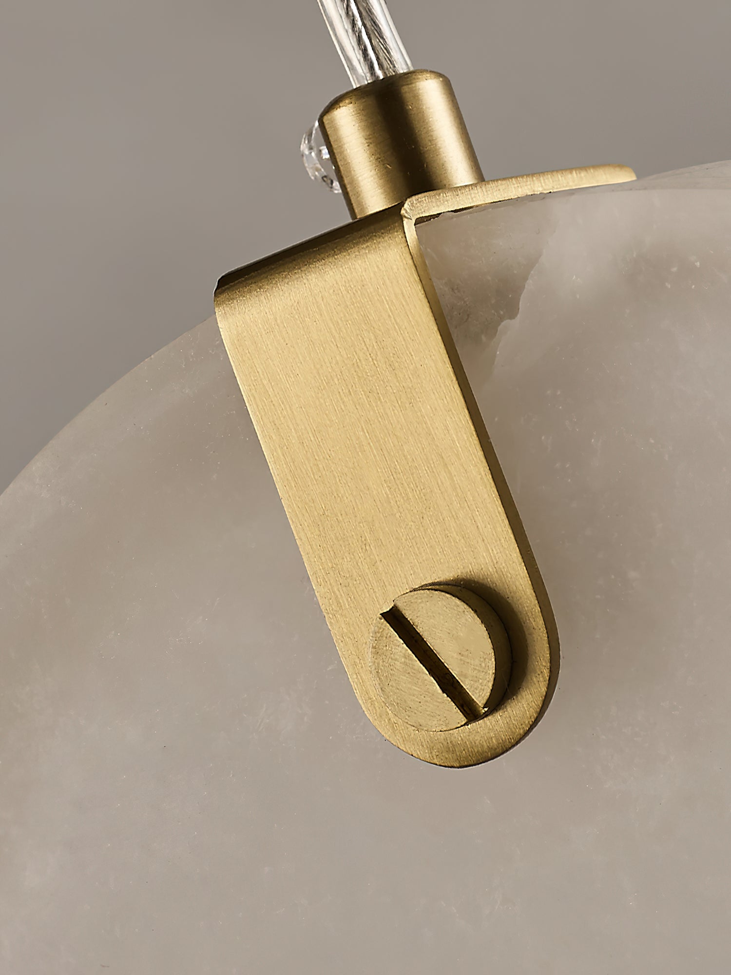 Detail of the folded brass strap and slotted pin that holds a Clérachic alabaster disc on its cable.