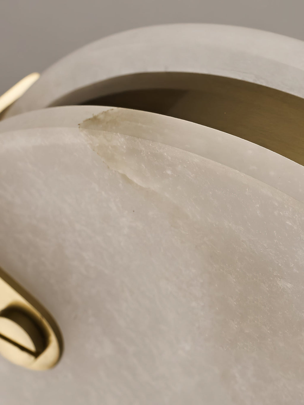 Detail of the seam on a Clérachic alabaster pendant, where the brass ring sits between the two stone faces.