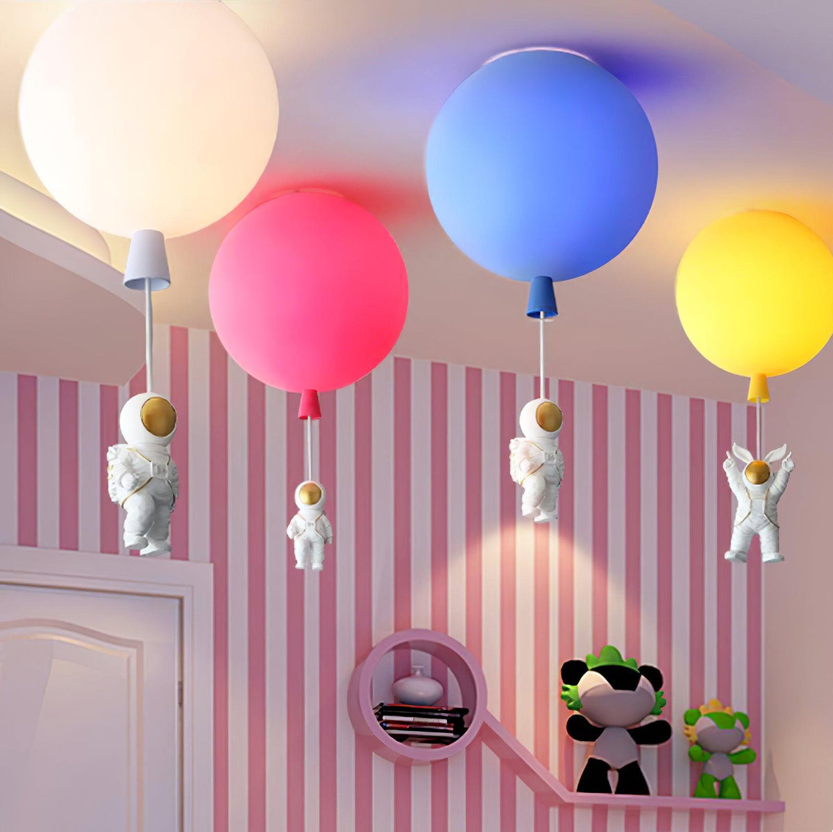Clérachic balloon ceiling lights in white, pink, blue and yellow above a pink striped wall, with astronauts hanging beneath.