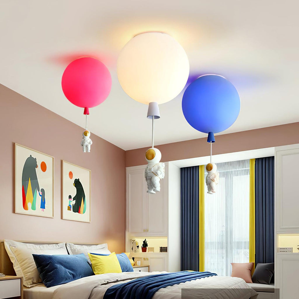 Three Clérachic balloon lights in pink, white and blue over a bedroom with a blue bedspread and navy curtains.
