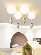 Four white Clérachic balloon lights with astronauts hanging at different heights above a play den with a wooden house frame.
