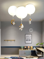 Three white Clérachic balloon lights with astronauts and a crescent moon above a grey room with a desk and a wall clock.