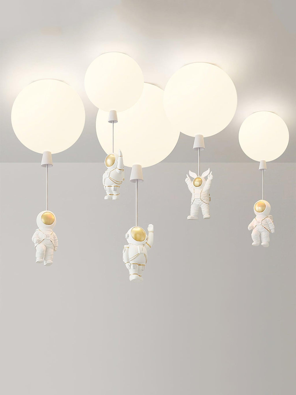 Five white Clérachic balloon lights with astronauts at different heights, shown against a plain pale backdrop.
