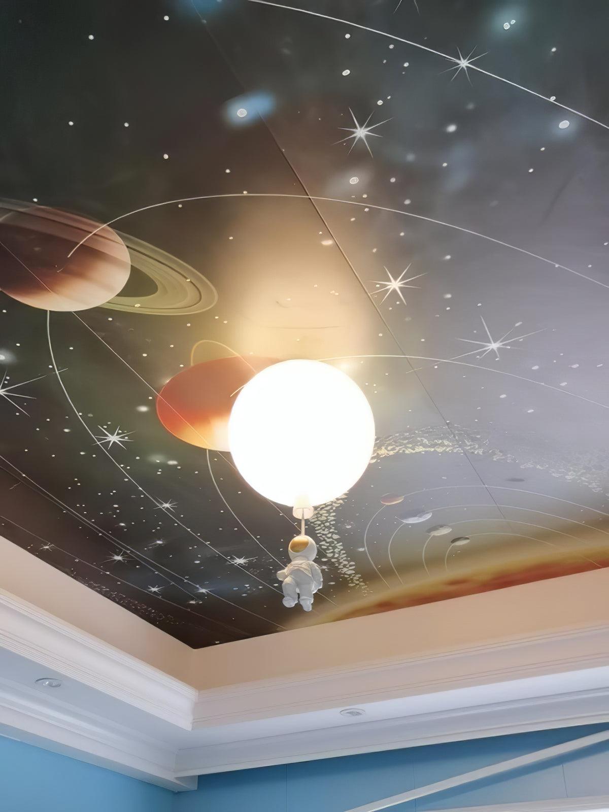 One white Clérachic balloon light with an astronaut under a ceiling printed with planets and stars, in a room with a blue border.