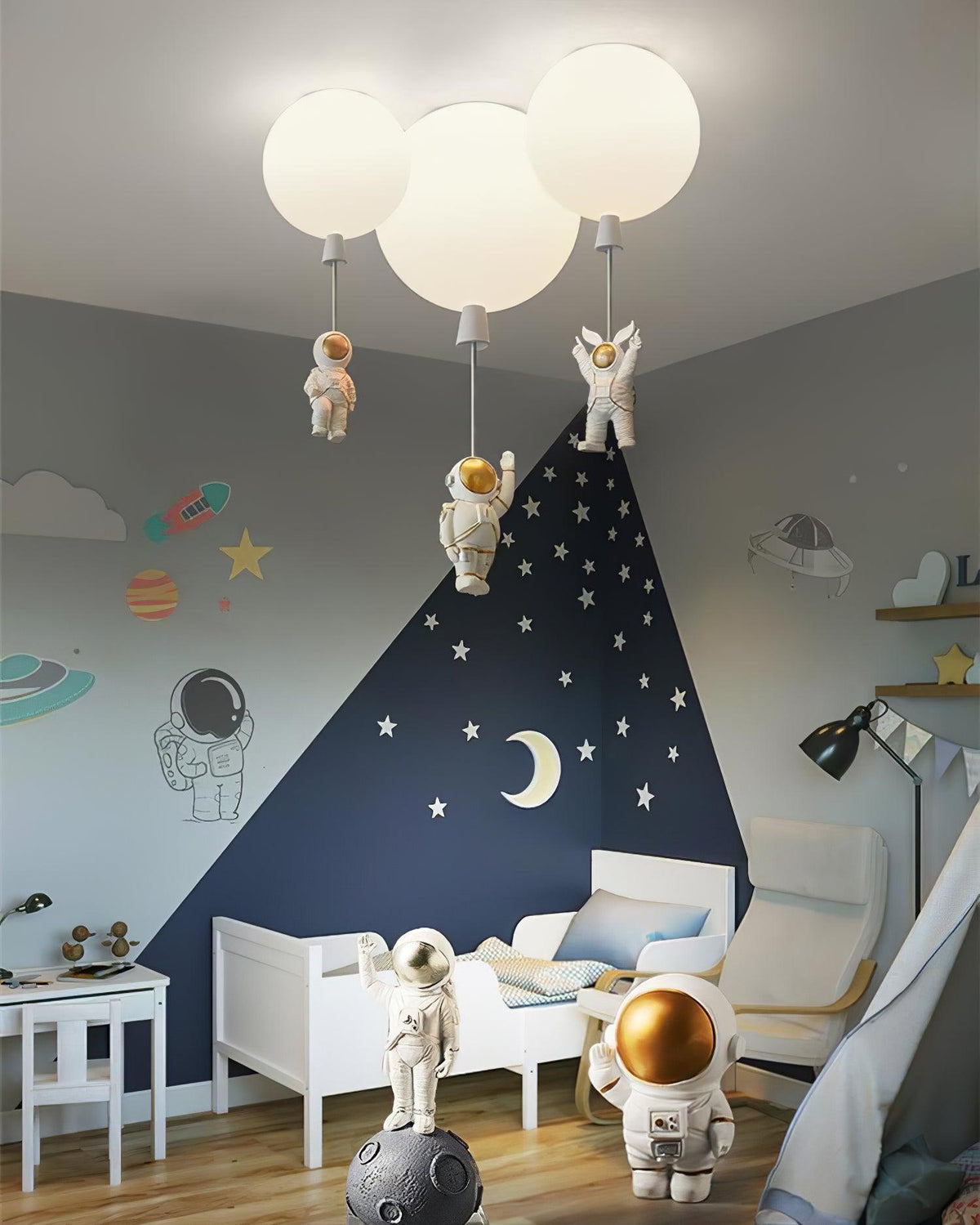 Three white Clérachic balloon lights with astronauts over a child's bed, with a navy starry wall and astronaut figurines.