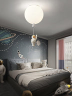 One white Clérachic balloon light with an astronaut above a bed against a grey wall painted with planets.