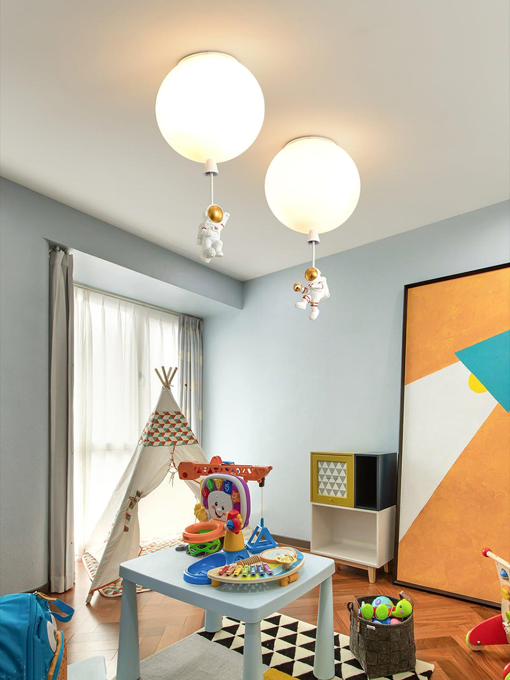 Two white Clérachic balloon lights with astronauts in a playroom with a teepee, a small table and an orange wall panel.
