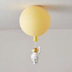 Yellow Clérachic balloon ceiling light with a matching cap, unlit, and a waving astronaut hanging below.