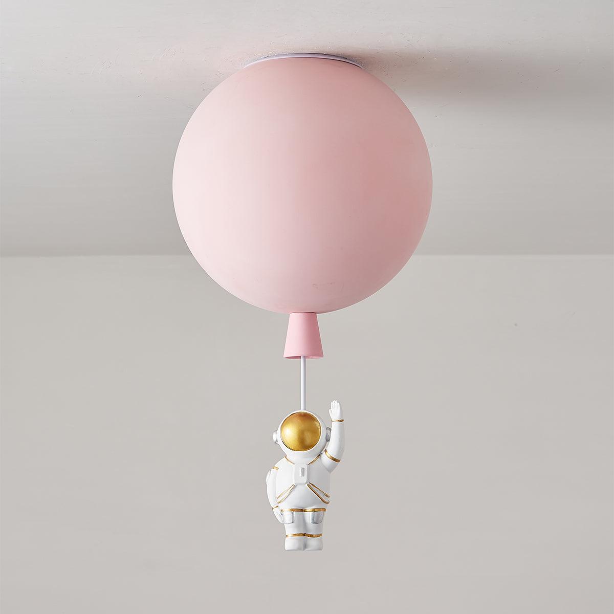 Pink Clérachic balloon ceiling light, unlit, with a pink cap and a waving astronaut hanging underneath.
